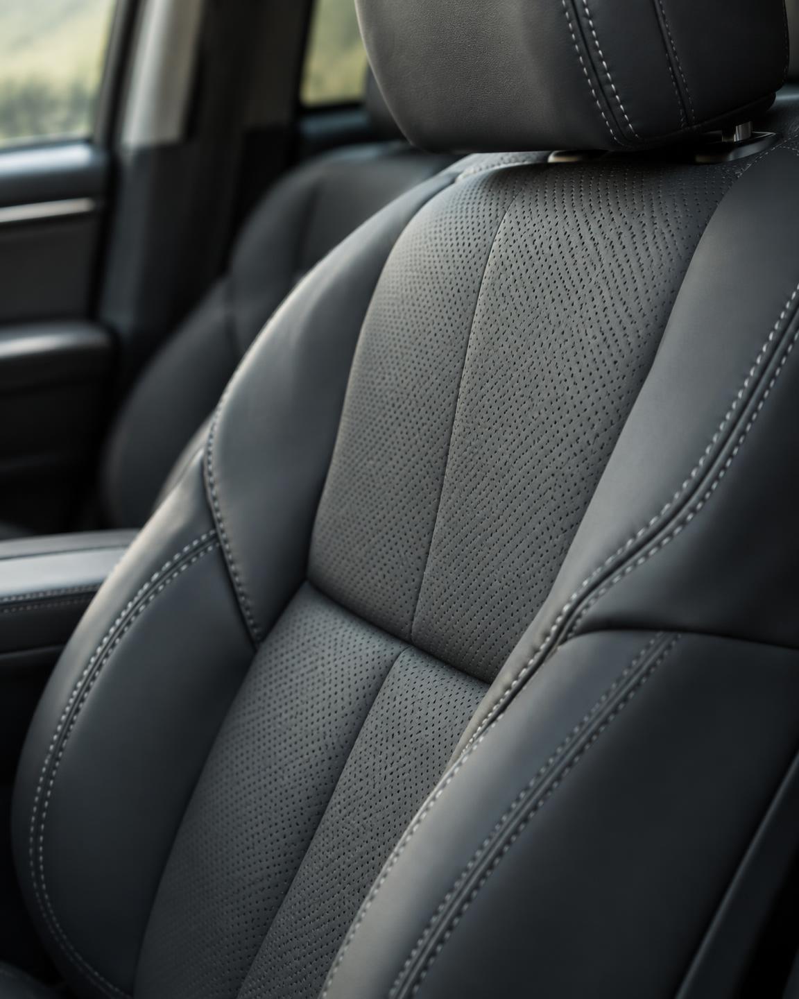 Close-up of a charcoal leather seat with perforated panels and fine contrast stitching.